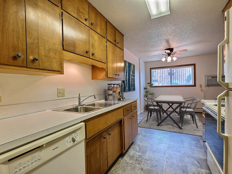 A kitchen with wooden cabinets and a white dishwasher. Fargo, ND Emerald Apartments